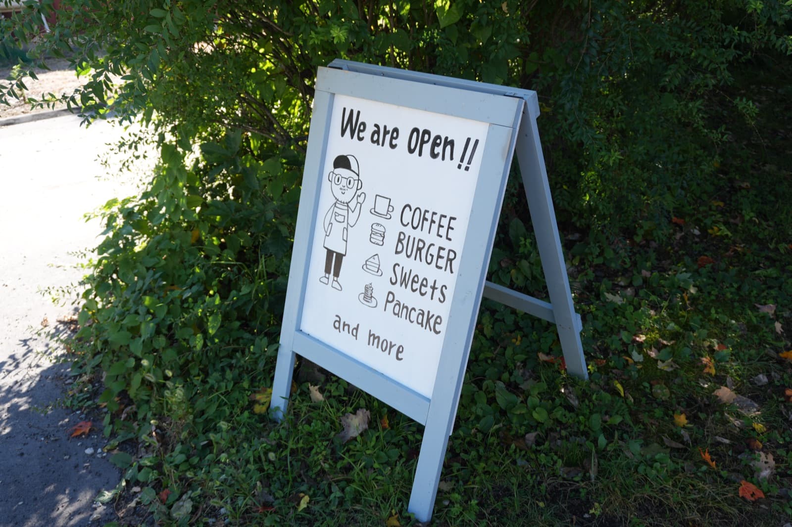 道路沿いに出ている立て看板。「We are OPEN!!」の下にCOFFEE・BURGER・Sweets・Pancakeと手書きで並ぶ。公式の定休日である火曜でも、祝日のこの日は営業していた(2026年9月22日訪問)