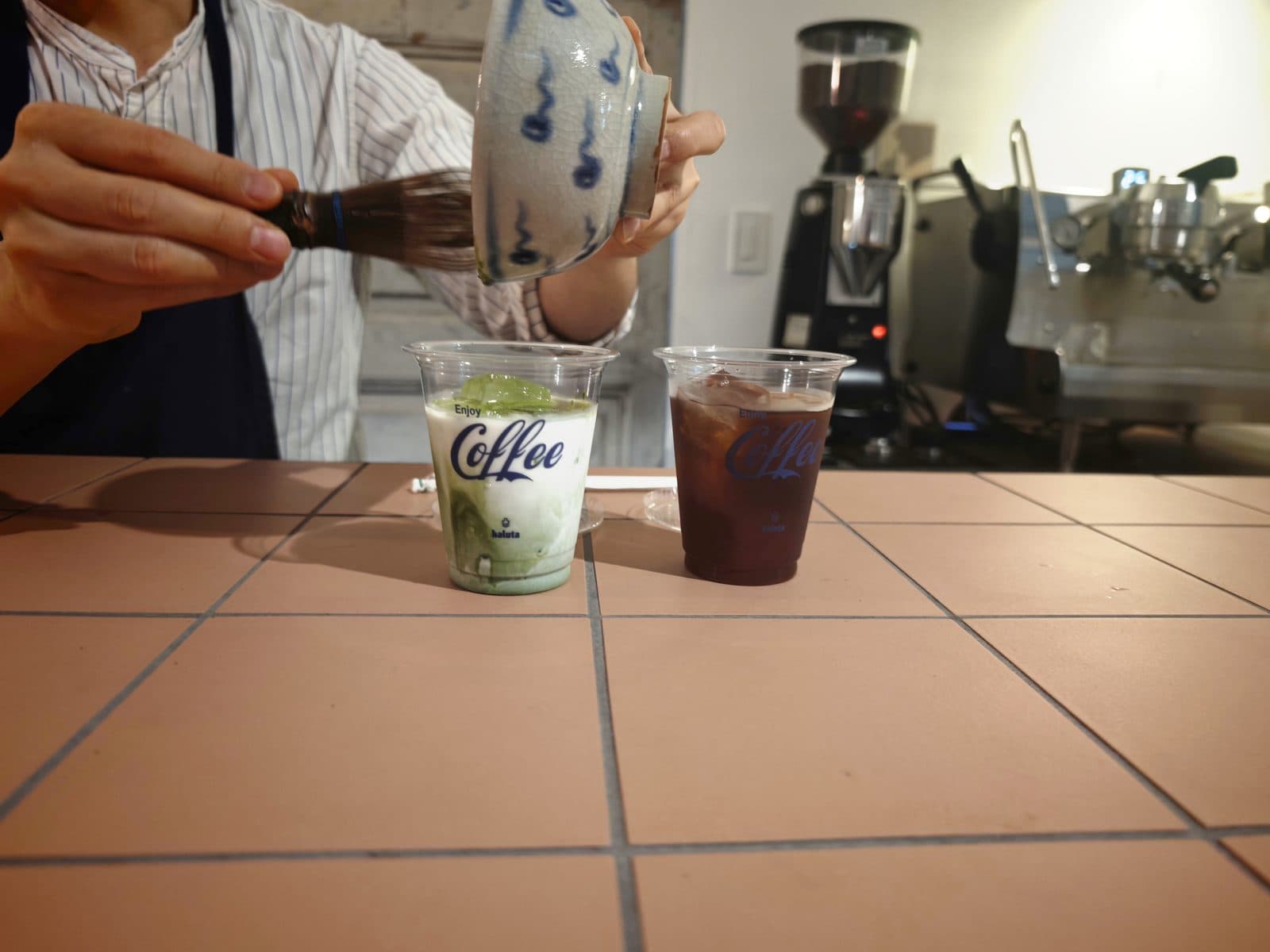 抹茶ラテは、店主がその場で抹茶を点ててミルクに注いでくれます。カップにはhalutaのロゴ(2026年9月12日・編集部撮影)